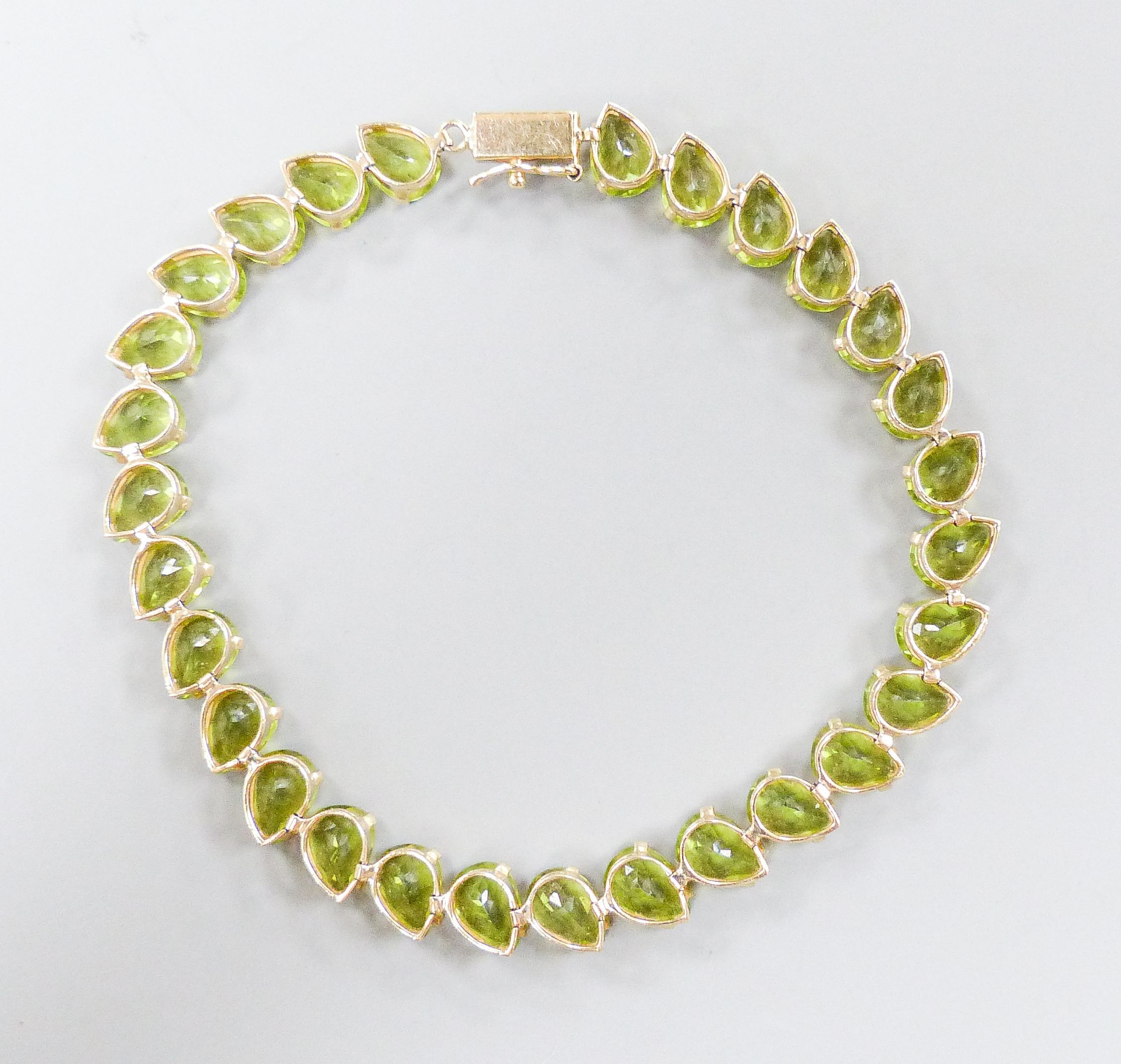 A modern 10k and pear cut peridot set line bracelet, 19cm, gross weight 9.4 grams.